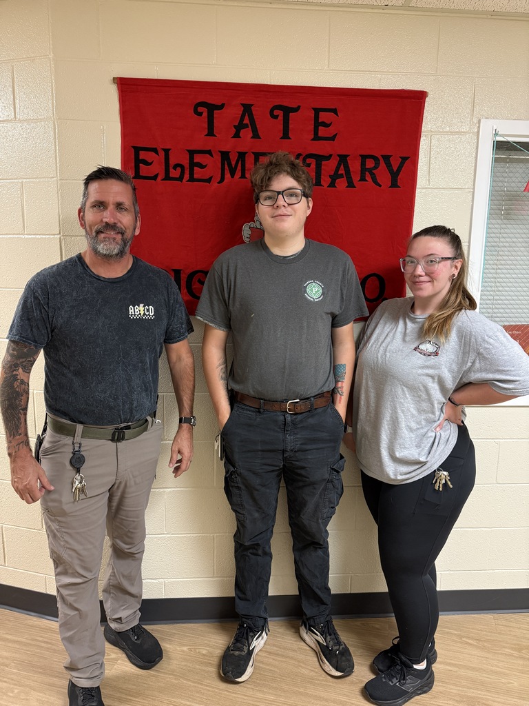 TES Custodians standing in front of red banner