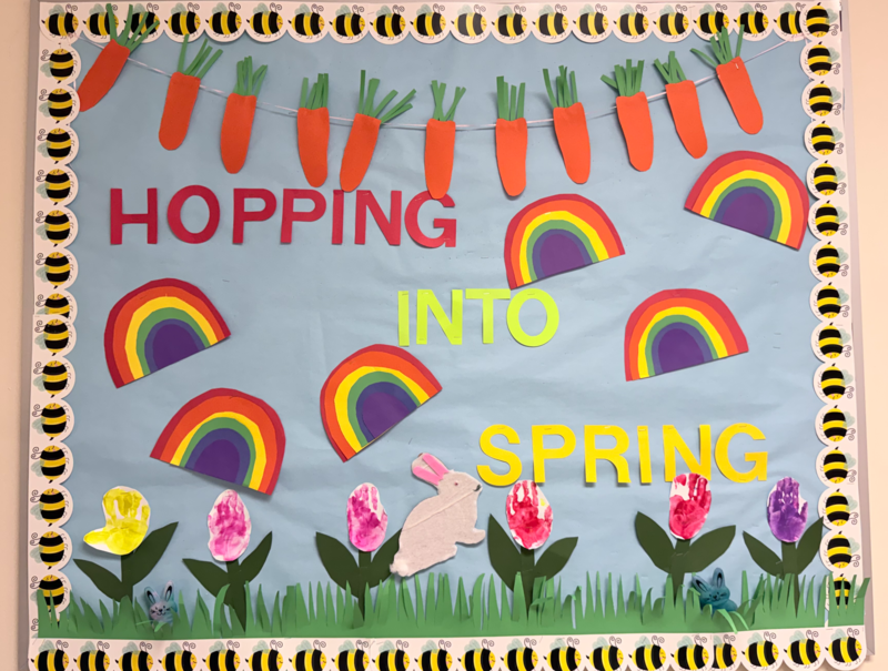 Preschool hallway  bulletin board depicting a spring scene with handpainted flowers, carrots, and bunnies.