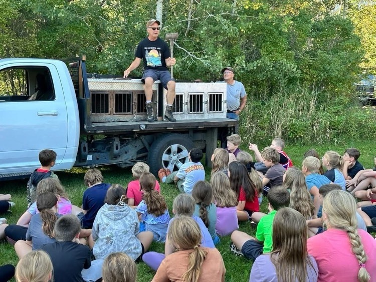 teacher sitting on truck talking to students outside 