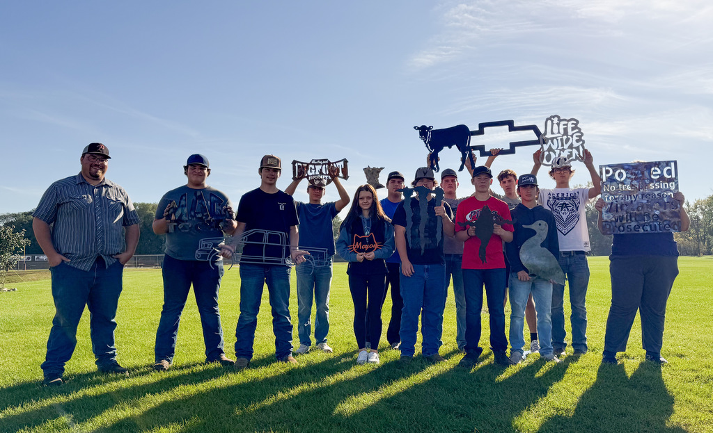thirteen students standing with metal signs they made facing the camera