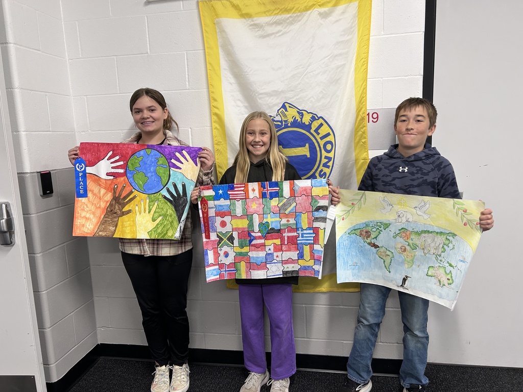 three students holding their peace posters smiling at the camera
