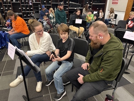 Band students with parents looking at camera playing instruments