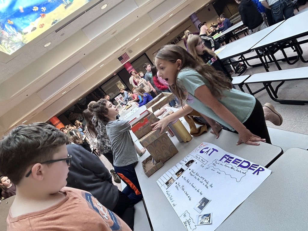 Student explaning a cat feeder invention to other students