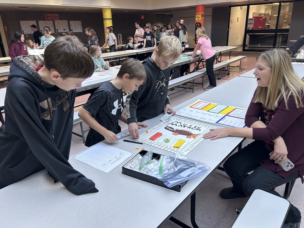 Ms. Sadlovsky with students in cafeteria looking at a game