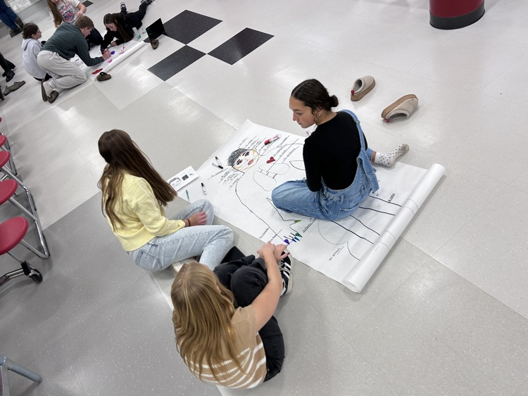 art students on floor with project looking camera 