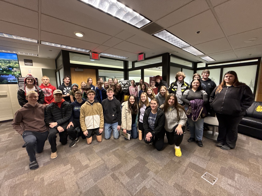 Entire student group looking at camera and smiling at UMD campus