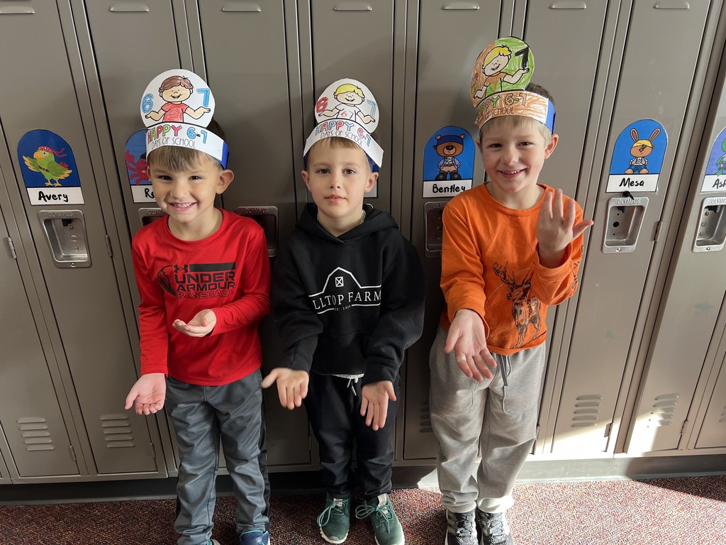 3 students smiling at camera with hands up and down