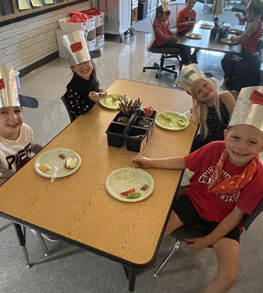 4 kindergarteners looking at camera and smiling with apples on their plates