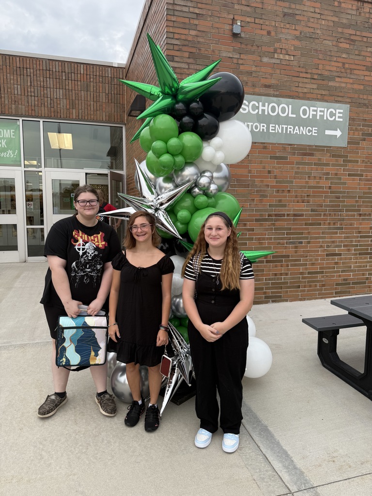 Students posing next to a ballon arch on the first day of school