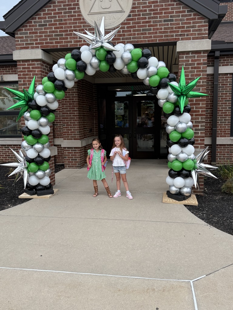 Students posing next to a ballon arch on the first day of school