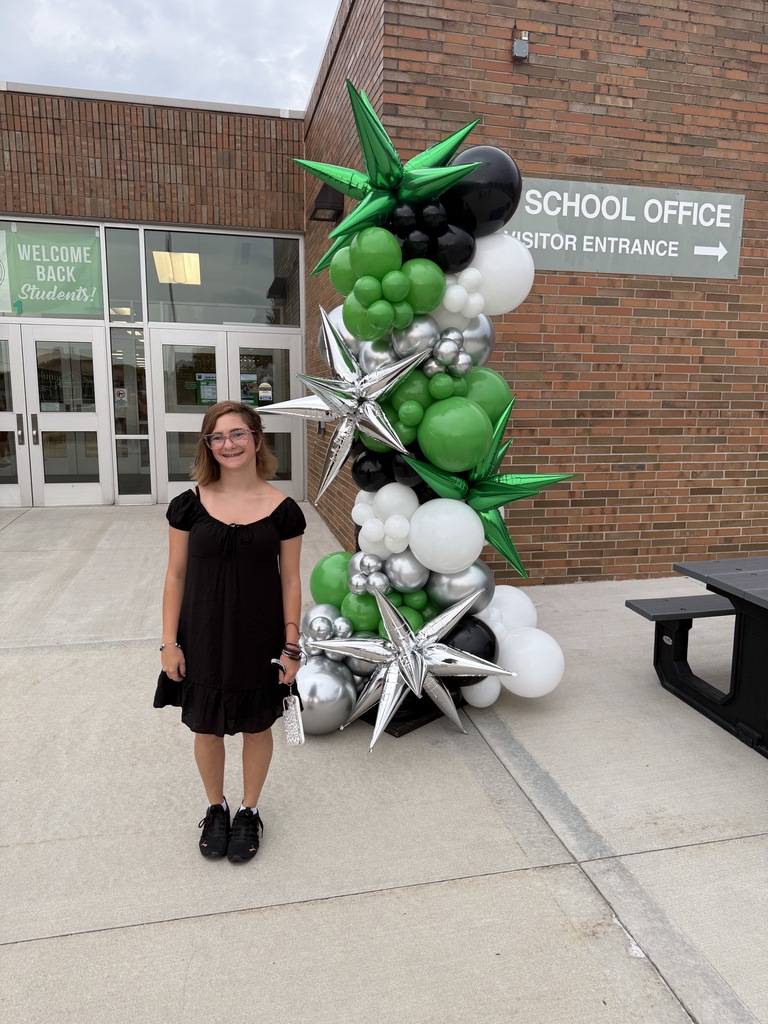 Students posing next to a ballon arch on the first day of school