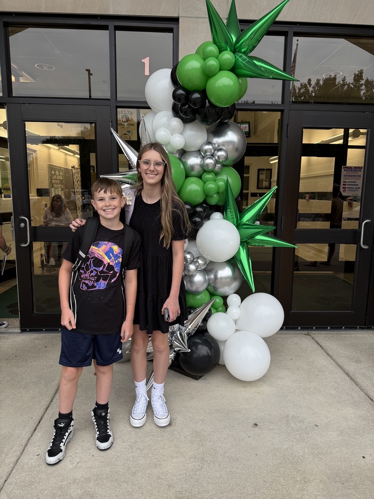 Students posing next to a ballon arch on the first day of school