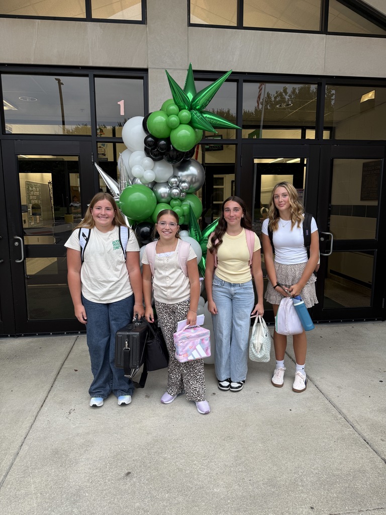 Students posing next to a ballon arch on the first day of school