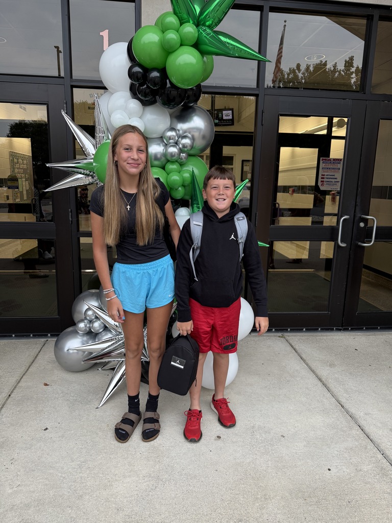 Students posing next to a ballon arch on the first day of school