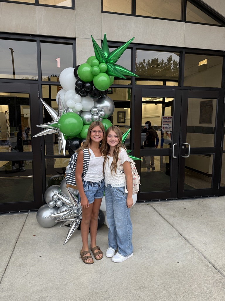 Students posing next to a ballon arch on the first day of school