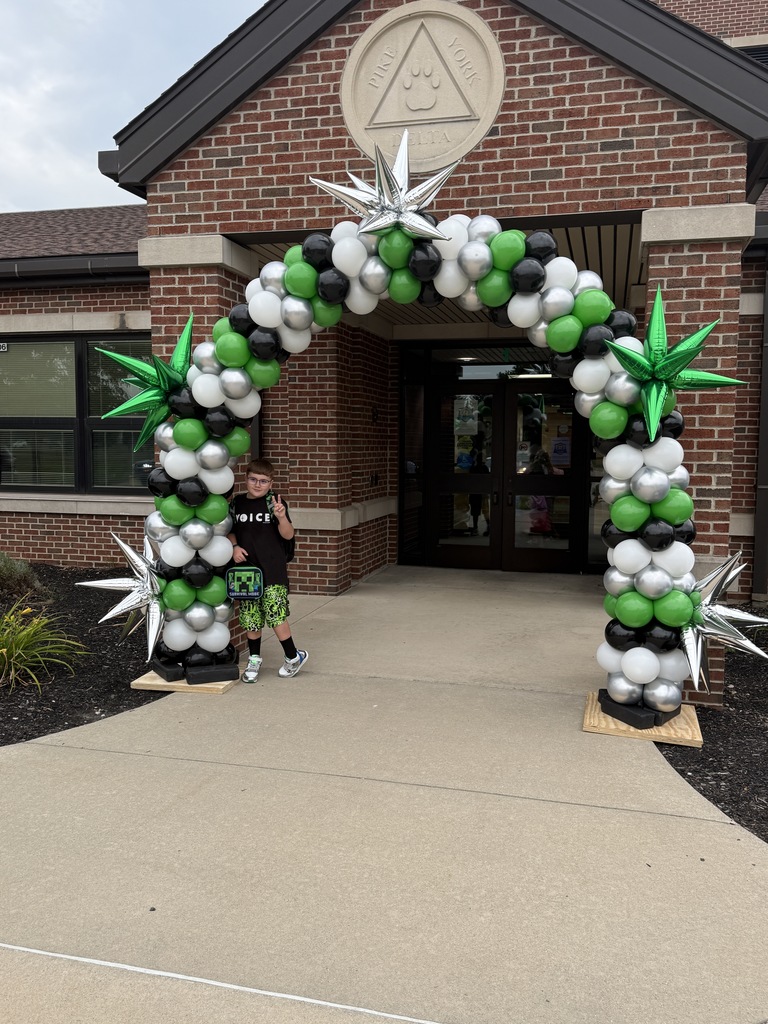 Students posing next to a ballon arch on the first day of school
