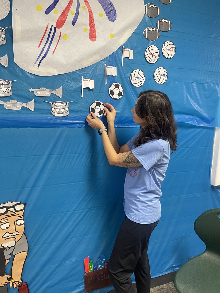 A teacher helping students with decorations for homecoming week