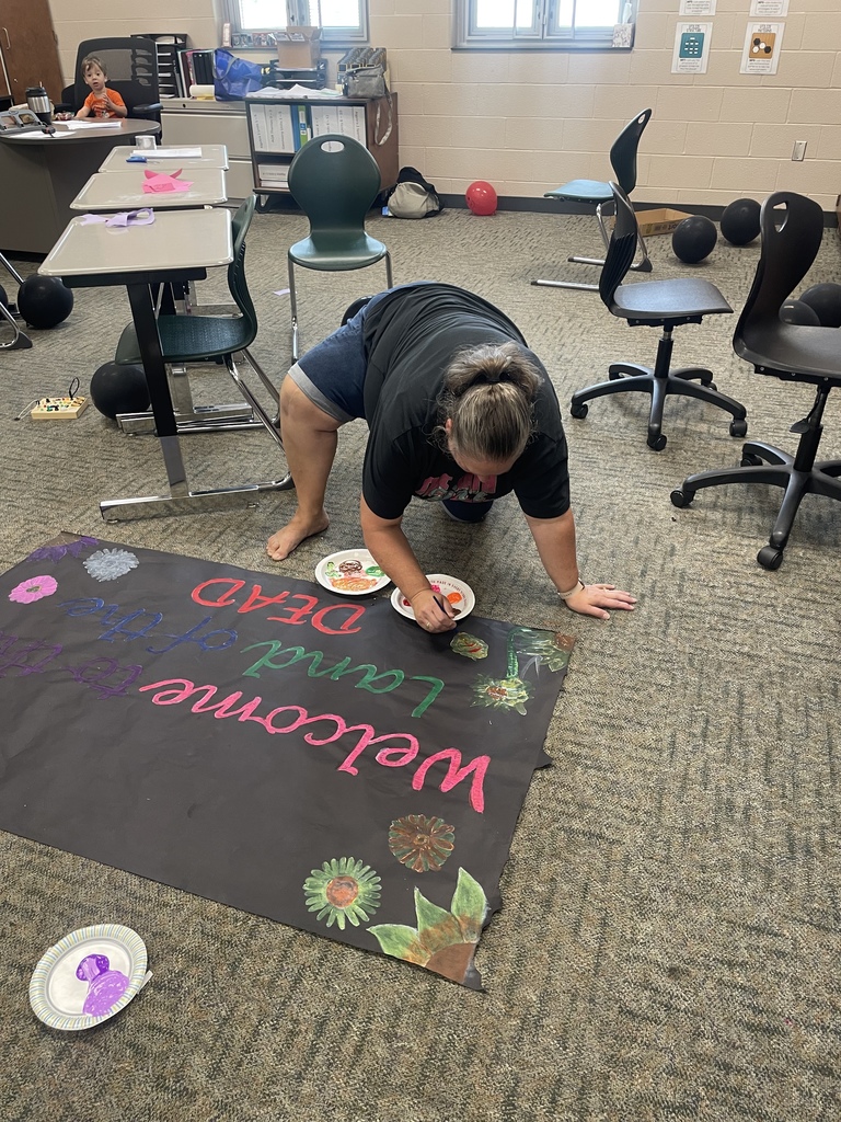 A teacher helping students with decorations for homecoming week