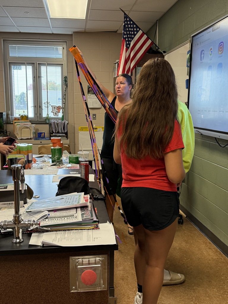 A teacher helping students with decorations for homecoming week