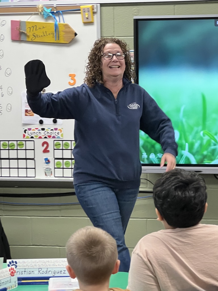 An adult walking around a classroom showing kindergartners a taxidermied bat