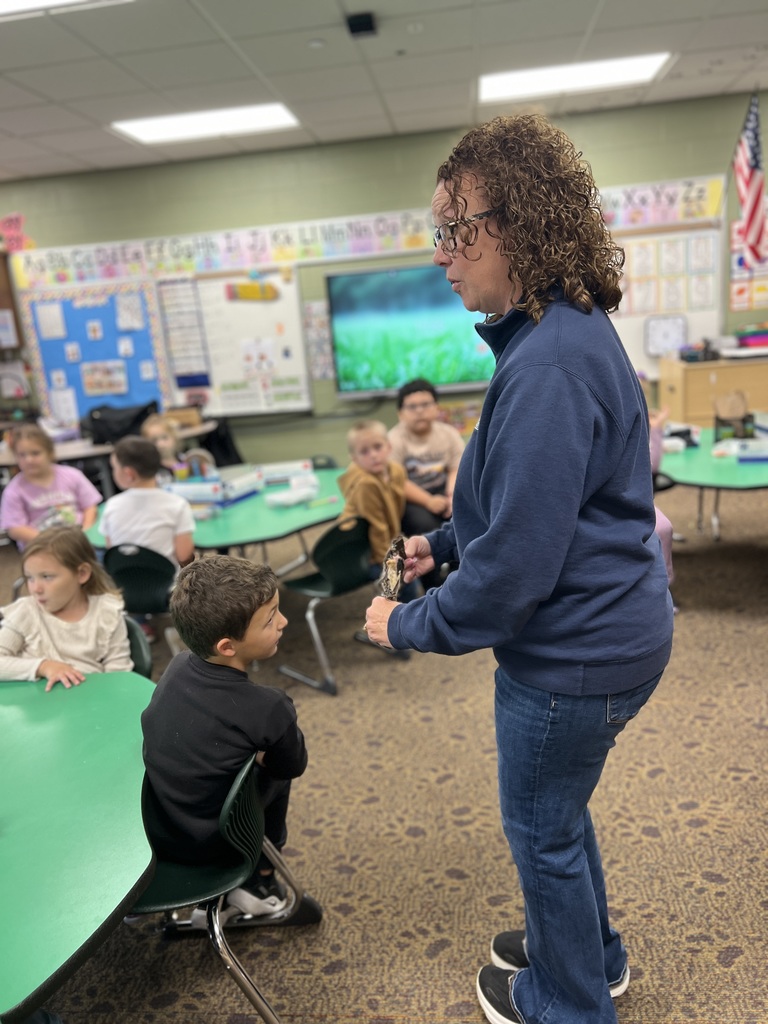 An adult walking around a classroom showing kindergartners a taxidermied bat