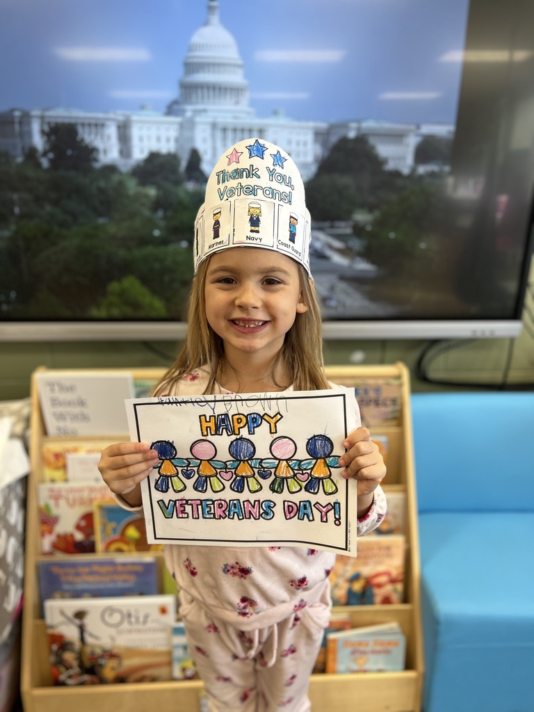 Kindergartners posing with a veterans day sign they colored