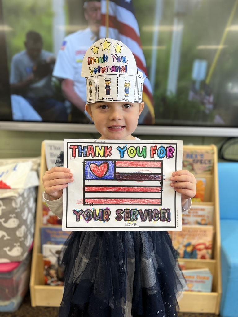 Kindergartners posing with a veterans day sign they colored