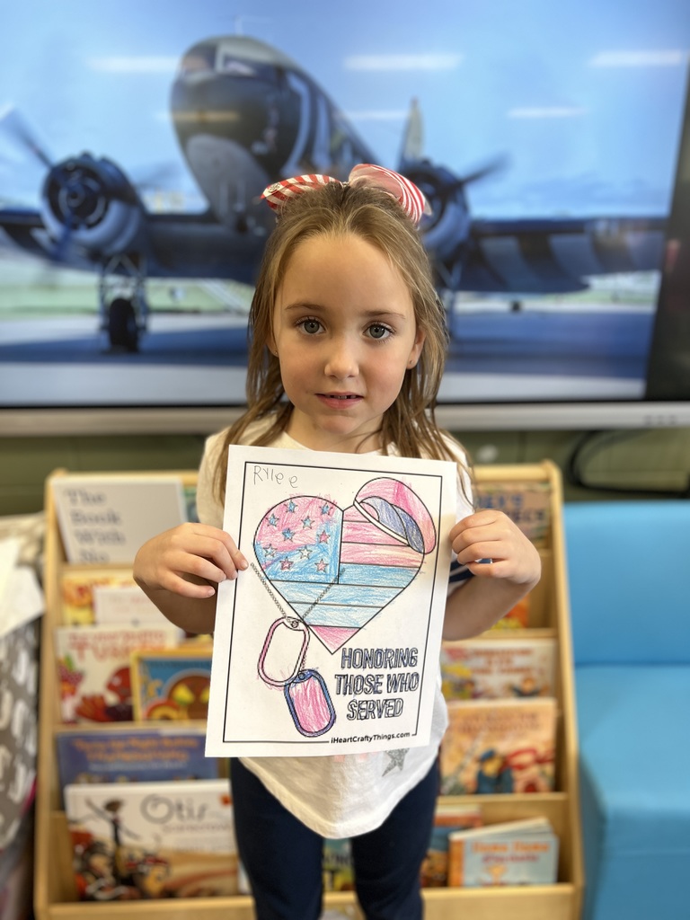 Kindergartners posing with a veterans day sign they colored