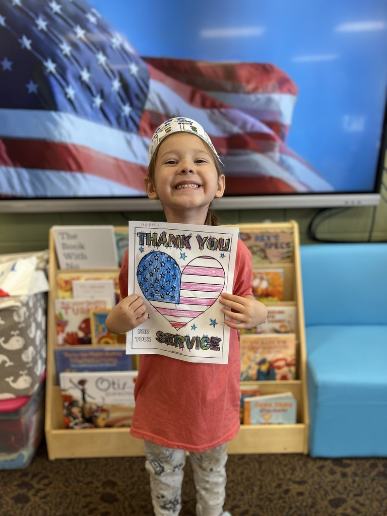 Kindergartners posing with a veterans day sign they colored