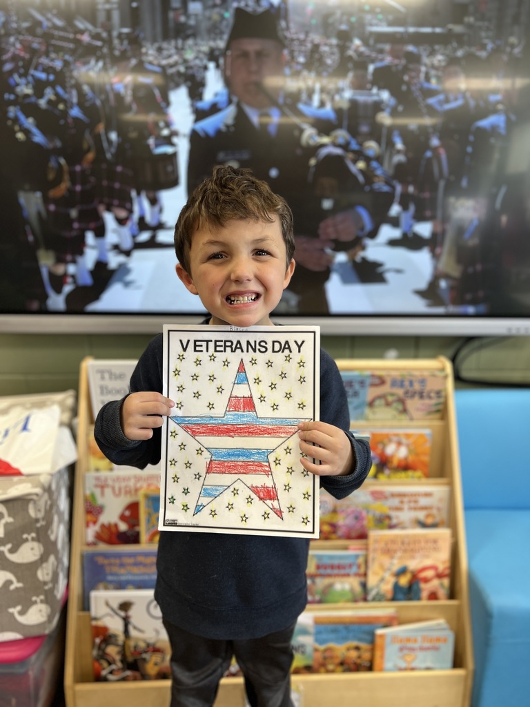 Kindergartners posing with a veterans day sign they colored