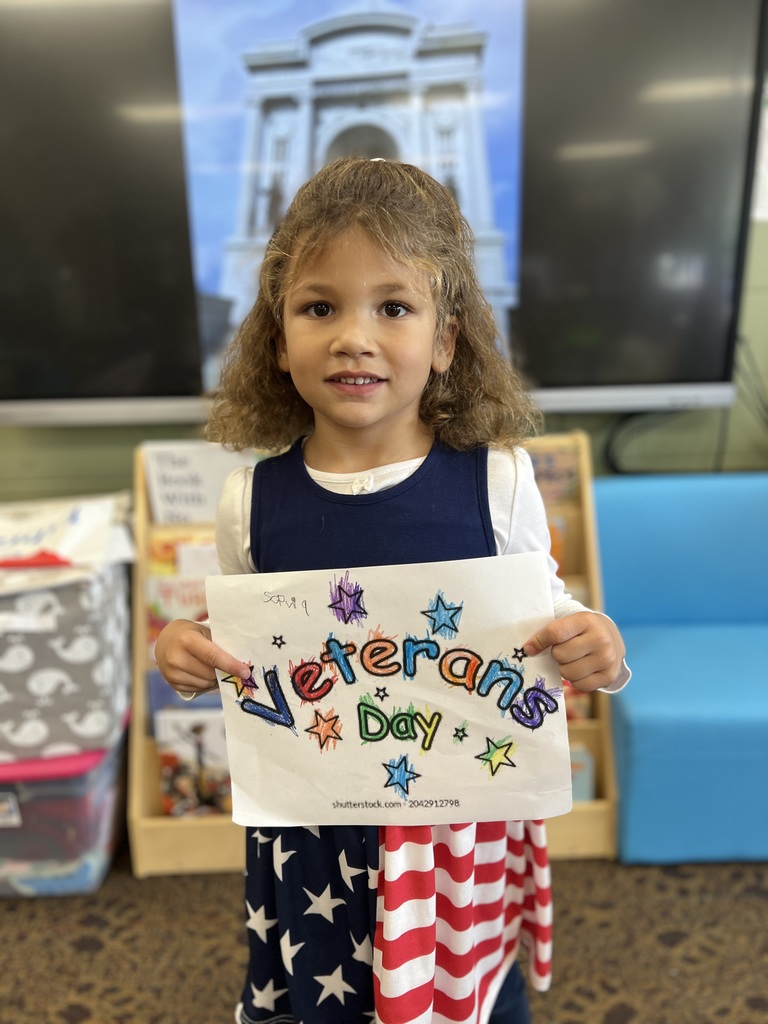 Kindergartners posing with a veterans day sign they colored