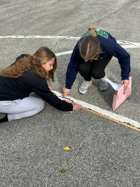 students measuring perimeter of outside objects