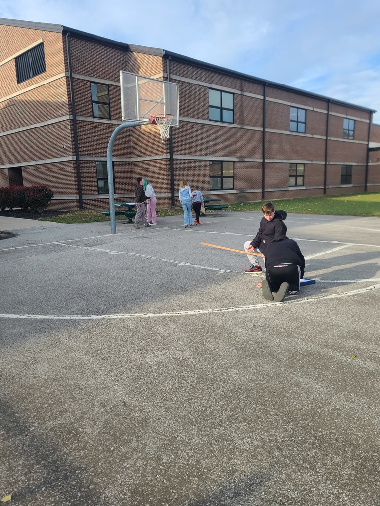 students measuring perimeter of outside objects