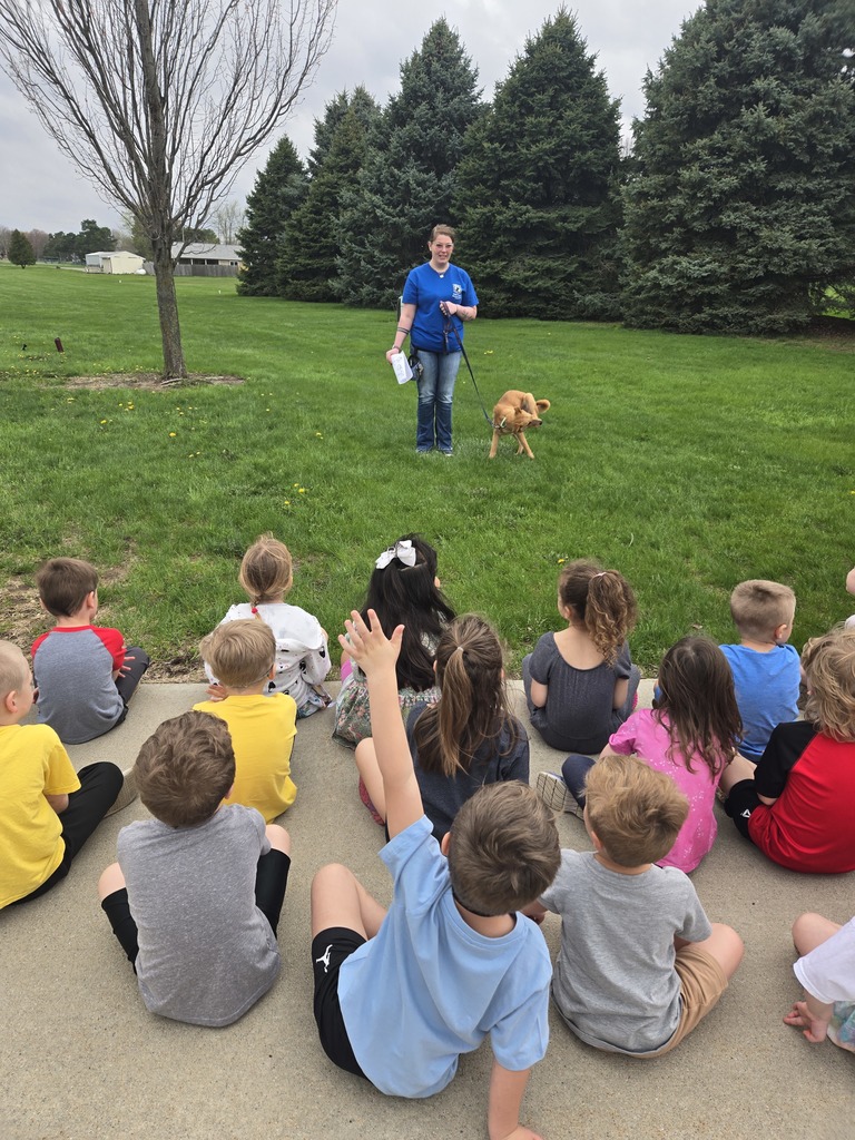 students sitting outside with a teacher and dog