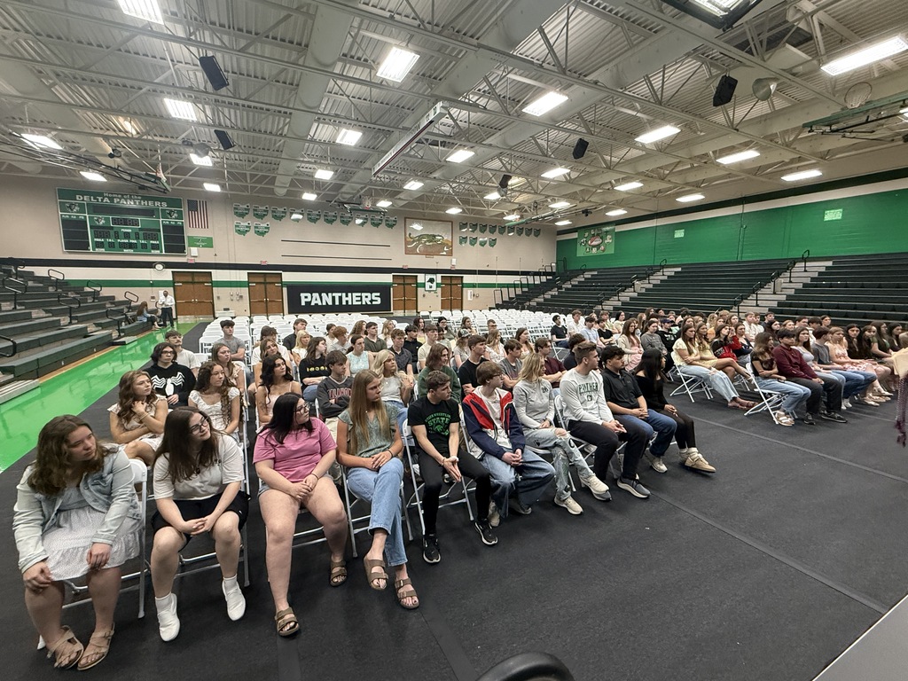 students sitting in a gymnasium at graduation practice