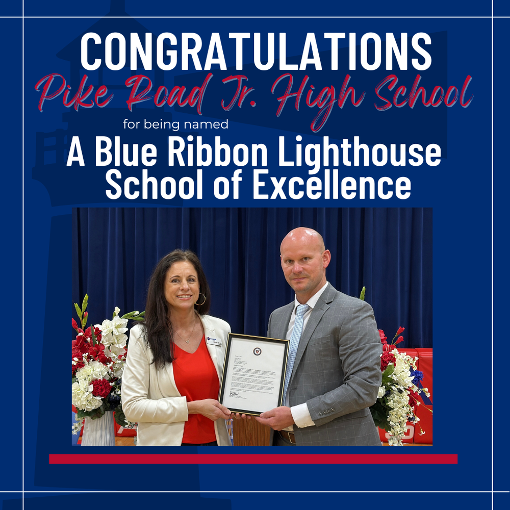 Congratulations to Pike Road Junior High School for being named a Blue Ribbon Lighthouse School of Excellence. The image shows two school officials standing together on a stage holding an official framed certificate, flanked by floral arrangements and a blue backdrop