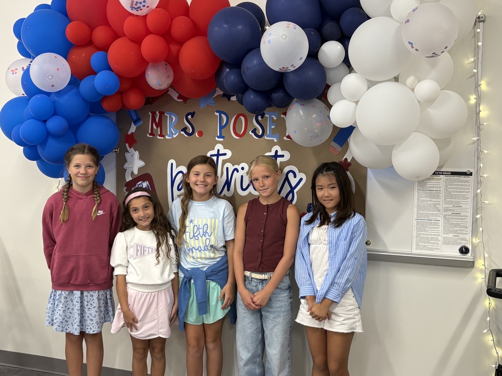 5 5th grader girls standing in front of balloon arch with Mrs. Posey's Patriots on the sign in the background