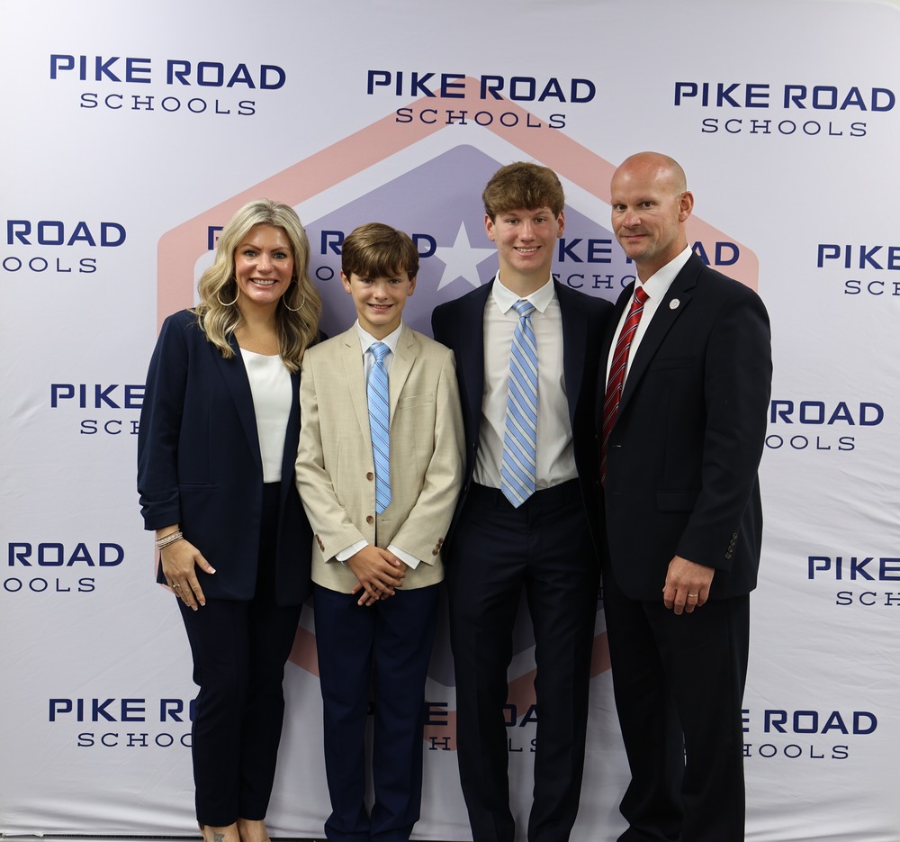 Family (Cassie, Joseph, Sam, and Dr. Jason Goodwin) in front of PRS backdrop