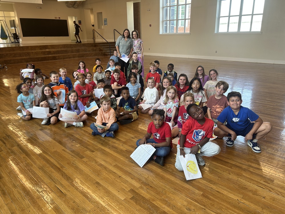 1st and 4th grade students sitting on wooden floor meeting face to face for the first time after being pen pals all year!