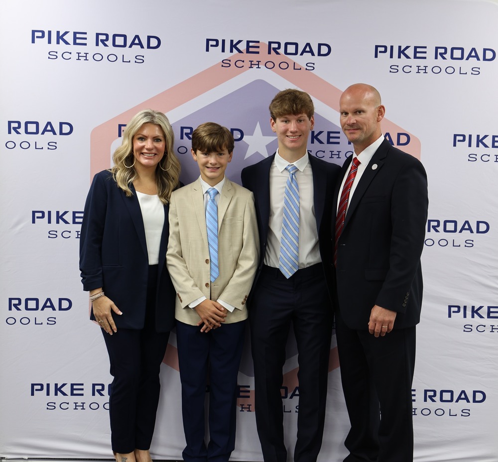 Family (Cassie, Joseph, Sam, and Dr. Jason Goodwin) in front of PRS backdrop