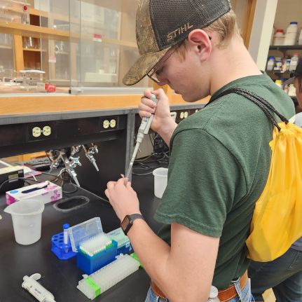 Young man in science lab adding fluid to a test tube