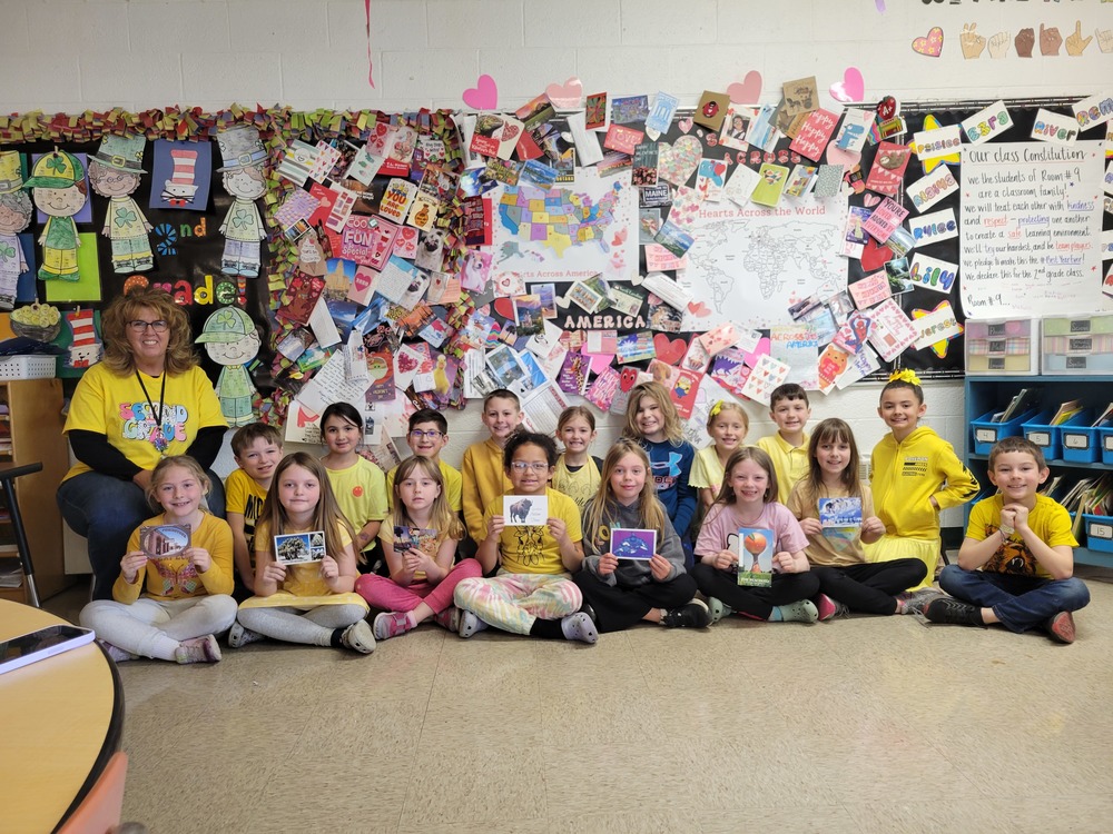 Class in yellow shirts holding mail