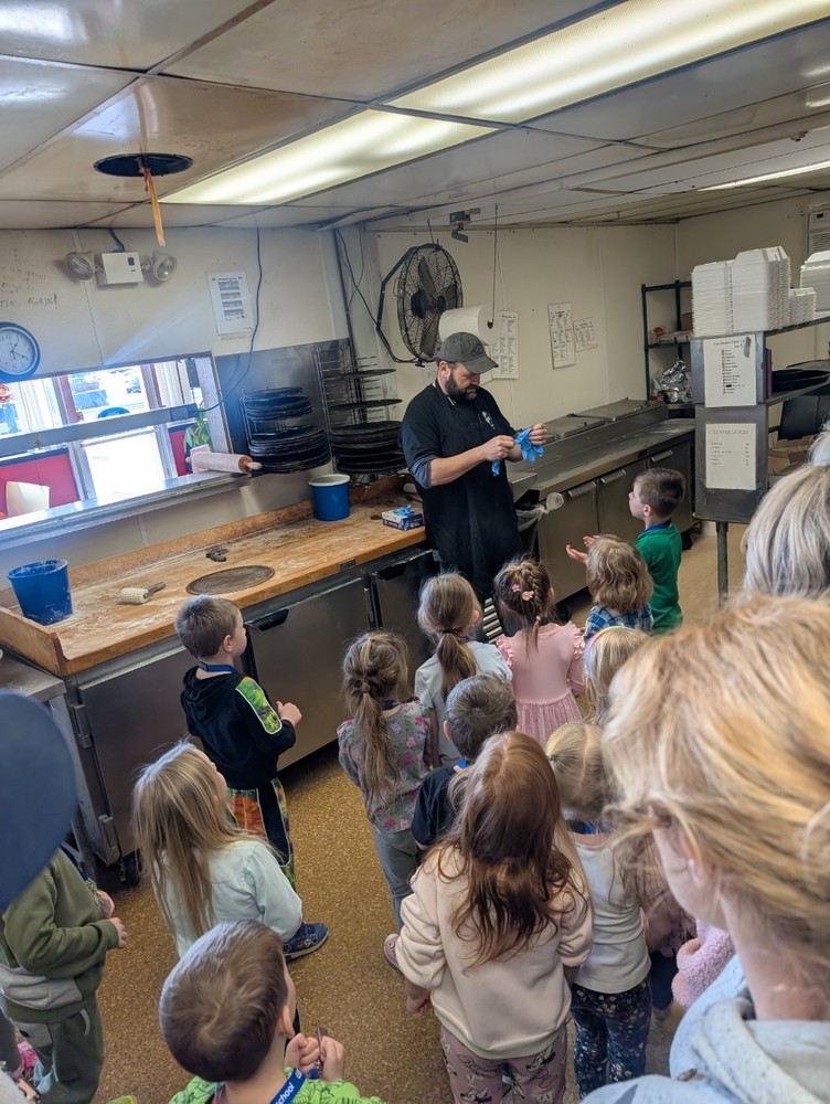 Students watching pizza being made.