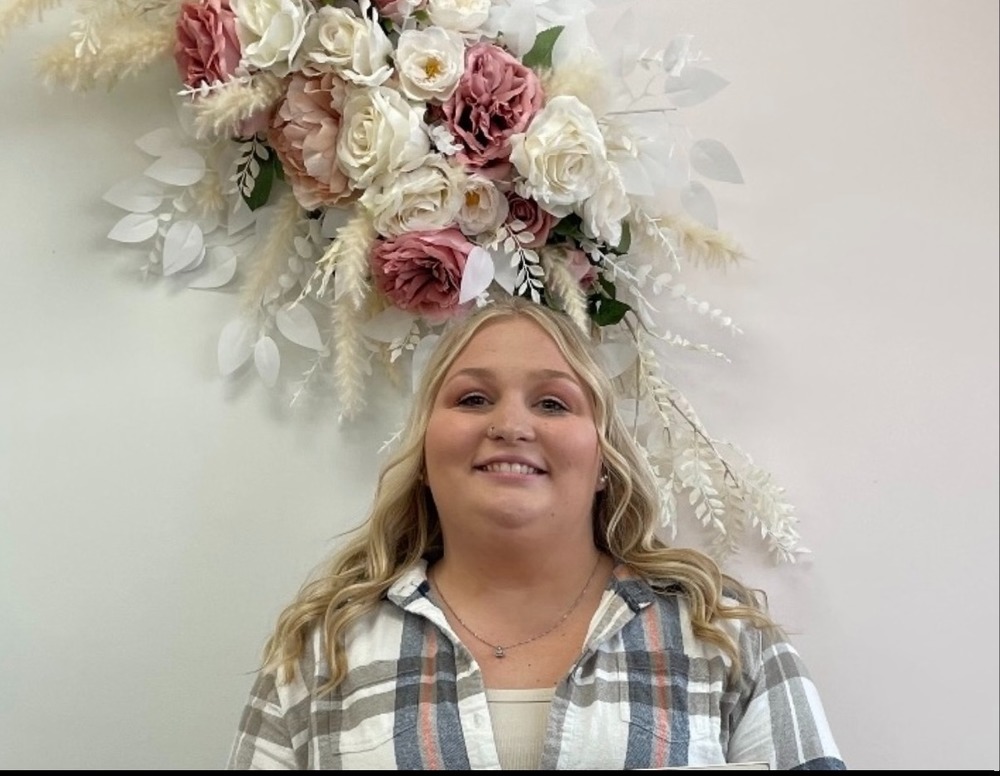 TEacher in front of a flower piece on the wall