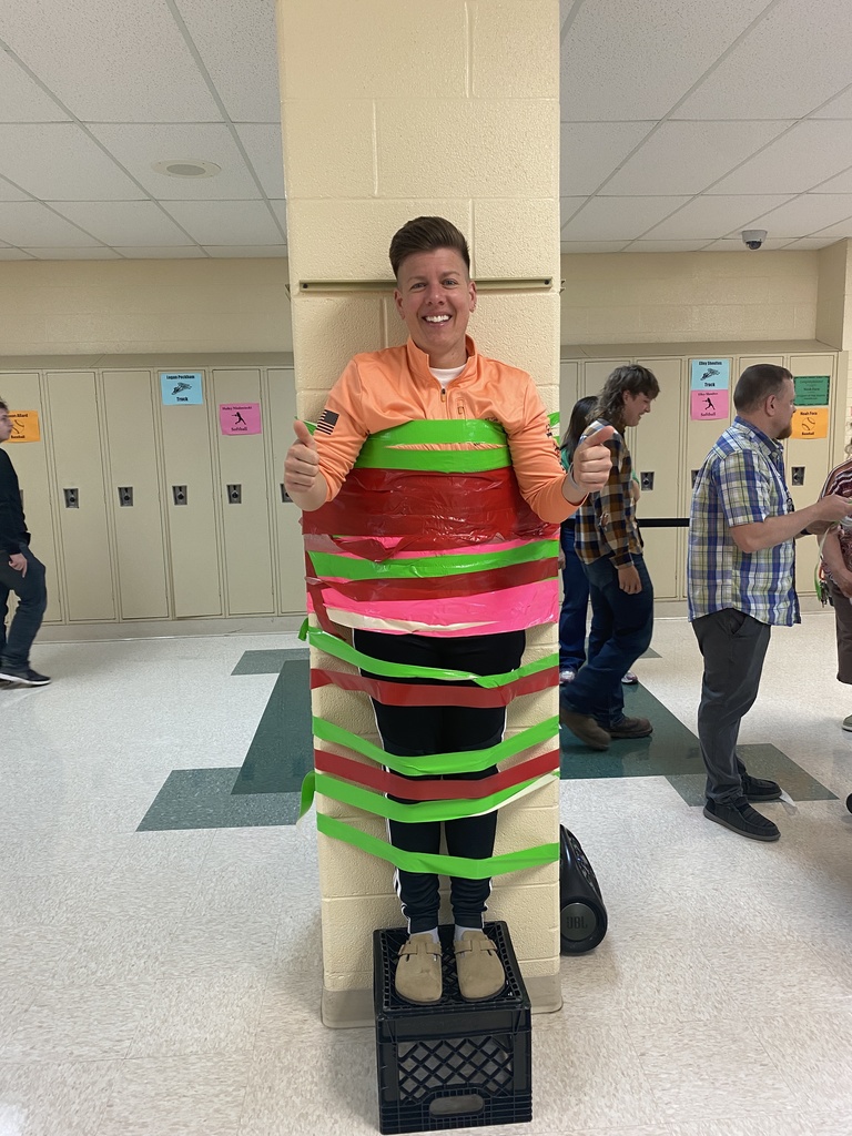 Dr. Braun standing on a crate taped to the column by colorful duct tape.