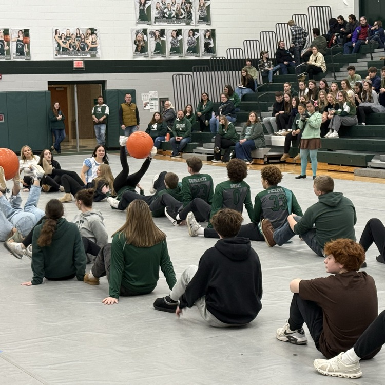 students pass a big orange ball in a relay race