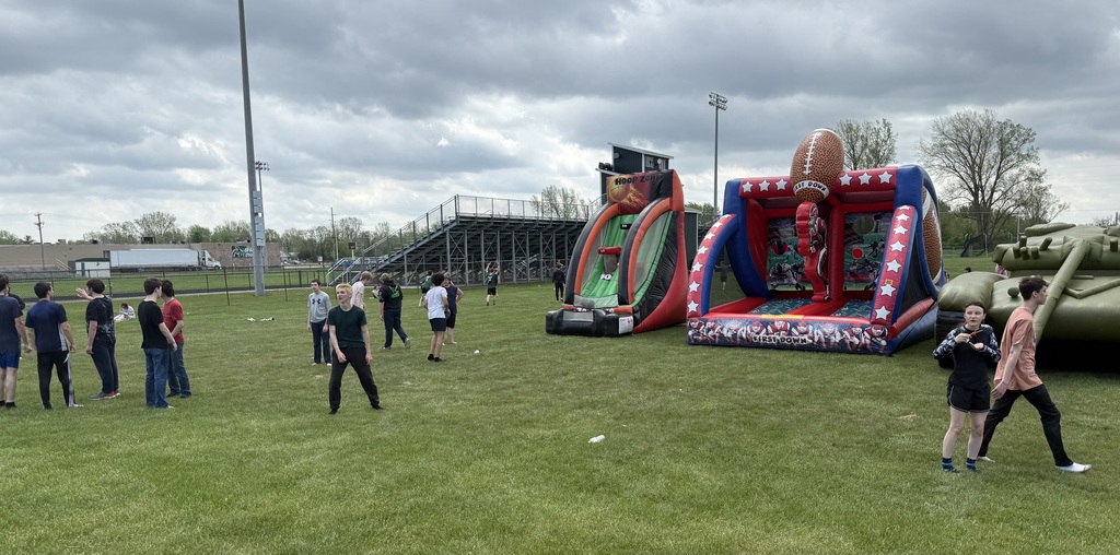 Students play near inflatable basketball and football targets.