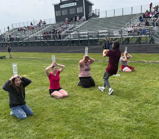 Students have beakers on their heads and students are filling them with water