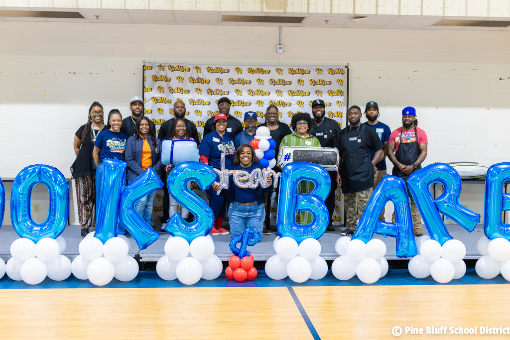 A group of adults and children pose for a photo behind balloons and letters spelling "Jobs Bare."