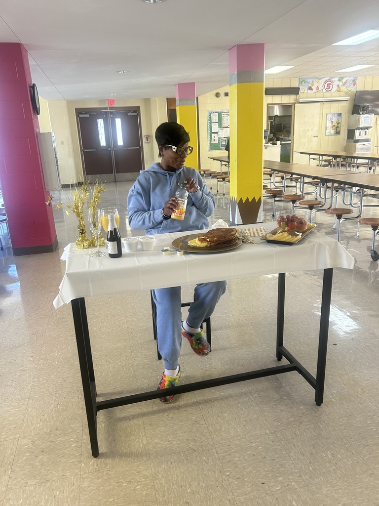 A person seated at a cafeteria table, surrounded by food, drinks, and a colorful column.
